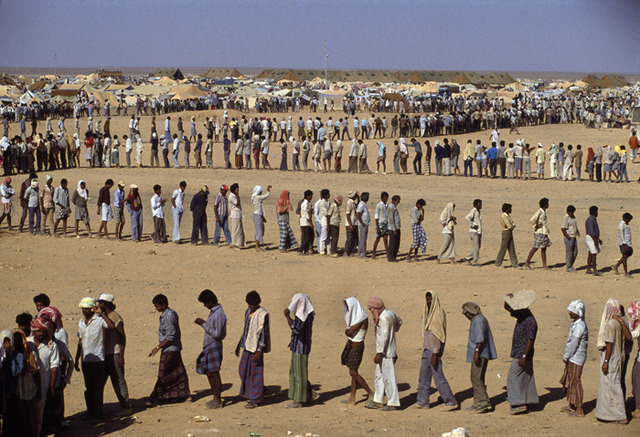 Refugees in the desert. The Sha-alaan One camp, is the worst camp. They have orderly food lines with thousands of refugees waiting calmly for food distribution from the “Charitas” charity organization. Jordan, 1990.